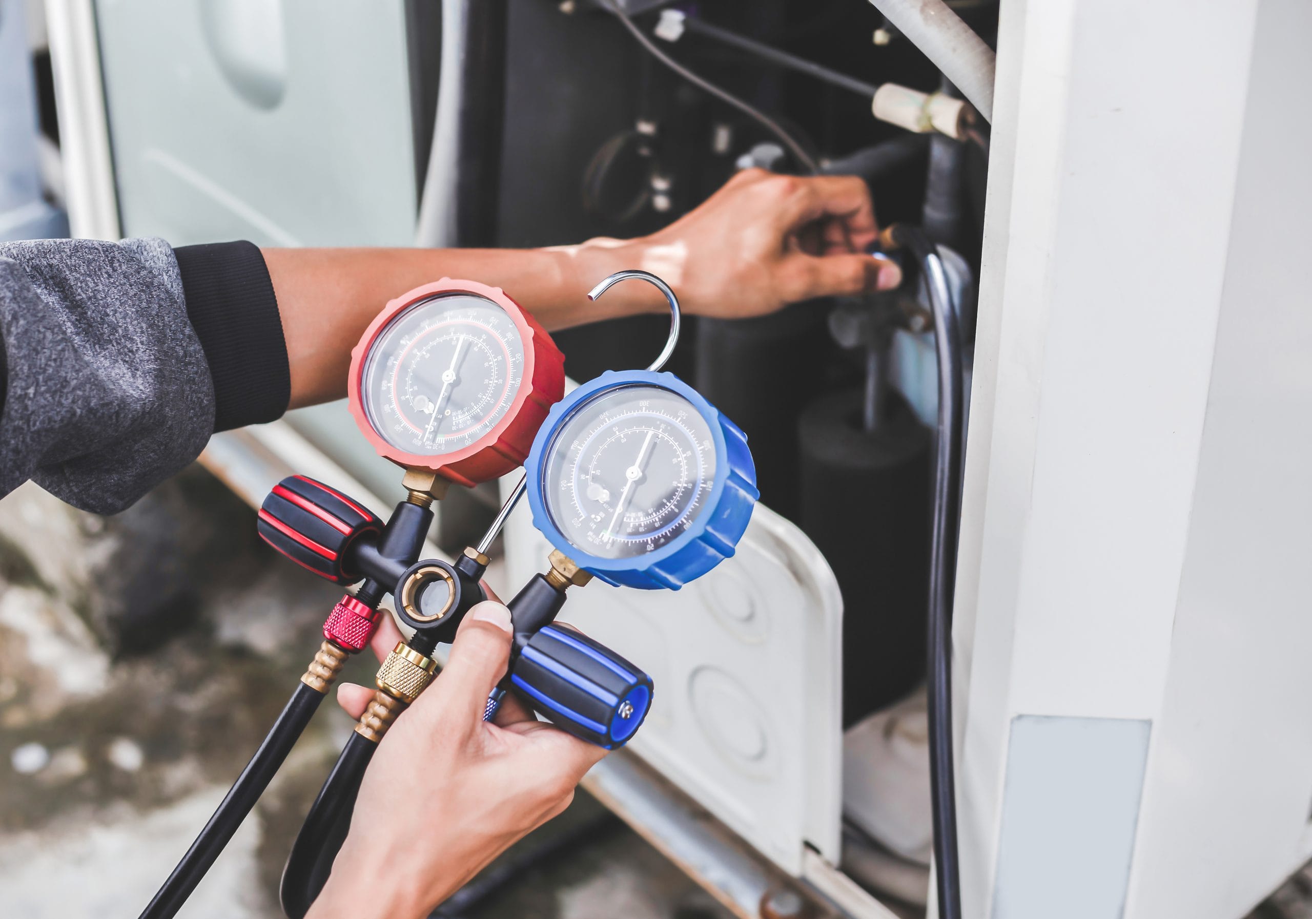 Technician checking the operation of the air conditioner Person using pressure gauges to check HVAC system.